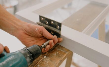 Close-up photo of someone installing a hinge on a door.